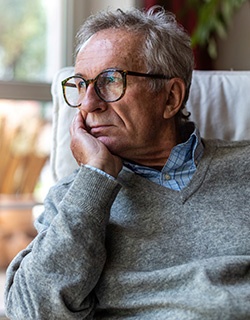 Älterer Herr schaut nachdenklich aus dem Fenster