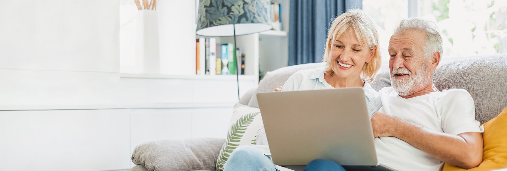 Ein älteres Paar sitzt gemeinsam auf einem Sofa und informiert sich mit einem Laptop über mögliche Stoma‑Komplikationen in einer häuslichen Umgebung.