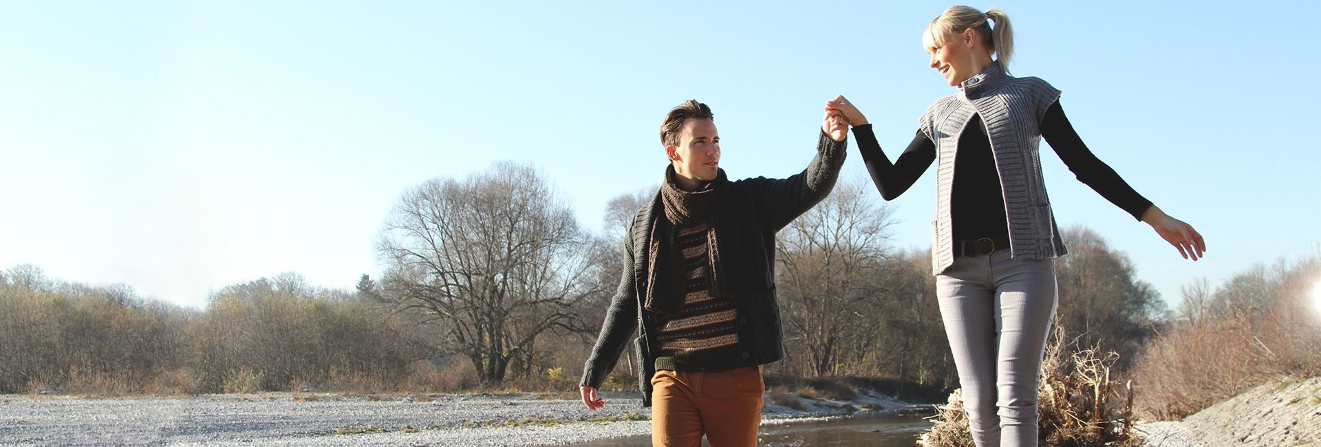 Ein Mann und eine Frau gehen Hand in Hand und genießen einen sonnigen Tag in der Natur.